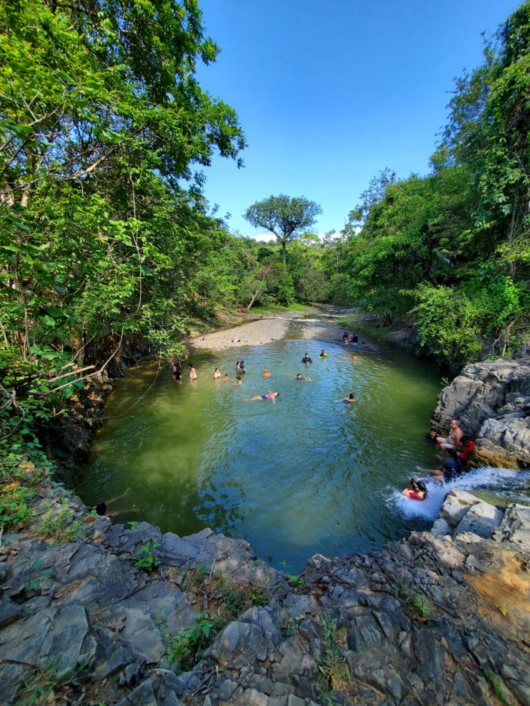 Familia de Piura disfrutando la laguna en la cueva de la Leona, rodeada de vegetación exuberante en la reserva natural La Ceiba
