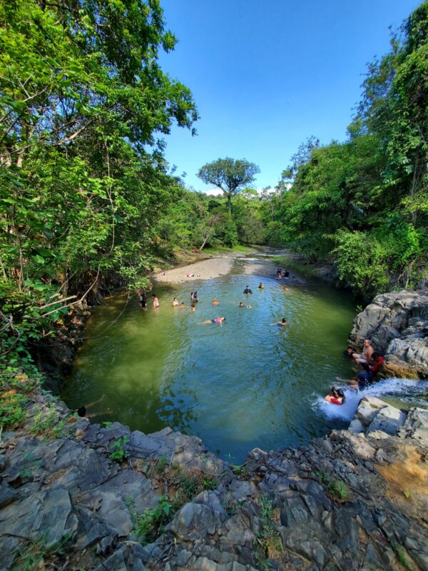 Familia de Piura disfrutando la laguna en la cueva de la Leona, rodeada de vegetación exuberante en la reserva natural La Ceiba