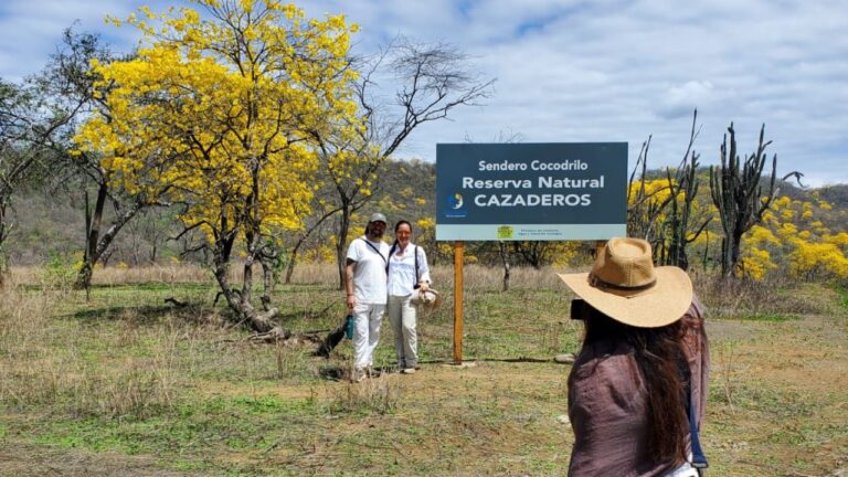 Turistas se fotografían bajo el letrero del Sendero Cocodrilo en la Reserva Natural de Cazaderos, Zapotillo, una ruta activa del bosque seco tras el florecimiento.