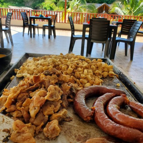 Plancha caliente con mote, zarandaja, longaniza y chicharrón servidos en la cafetería Nia Kapro